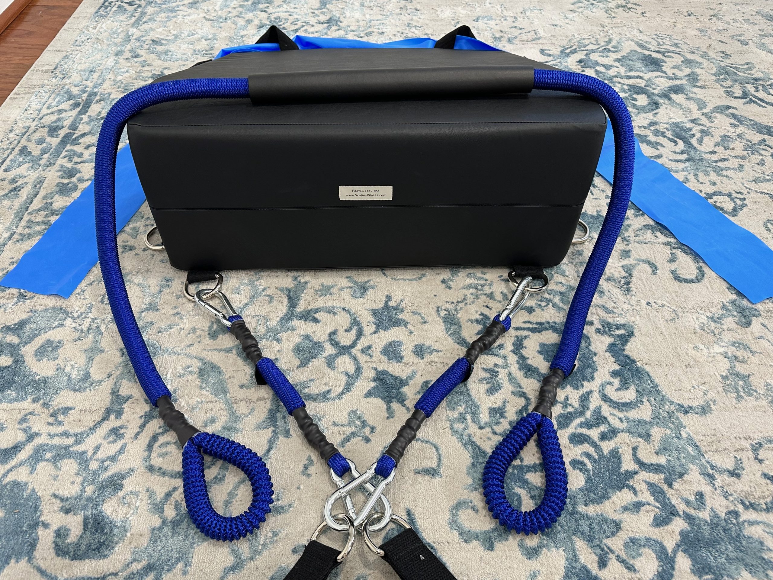 K-Fit wedge with blue bungee-style resistance cords looped over the top and flat resistance bands attached at the sides