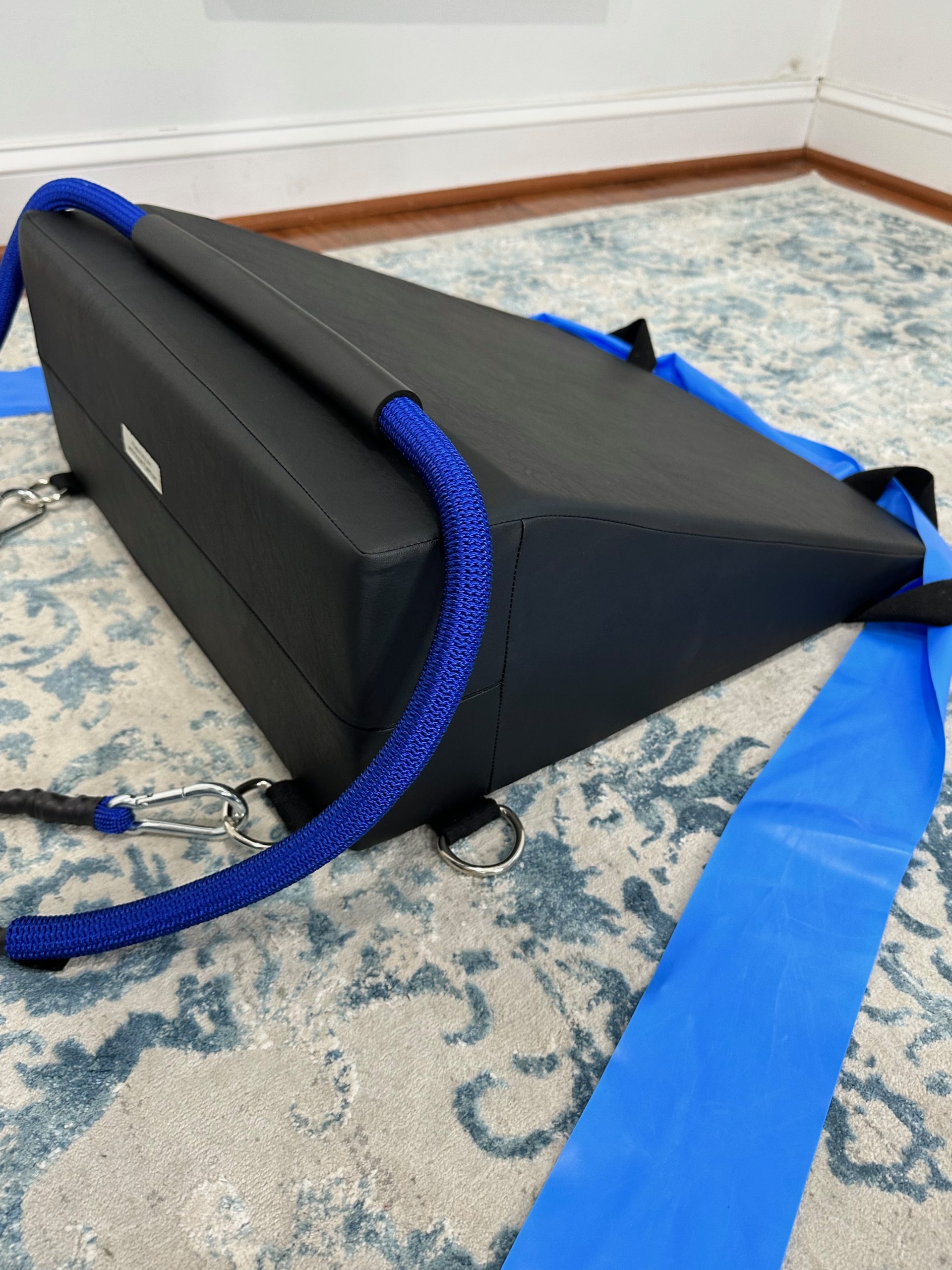 K-Fit wedge with blue bungee-style resistance cords looped over the top and flat resistance bands attached at the sides