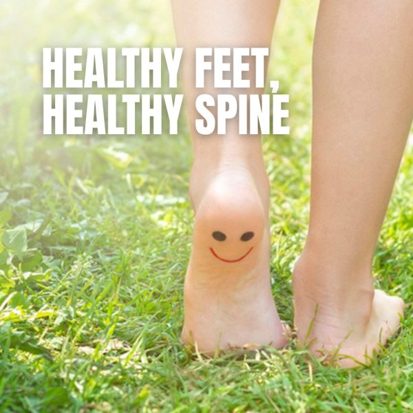 Bare feet walking on grass with a smiley face drawn on the heel, cover image for a blog post on the connection between healthy feet and a healthy spine