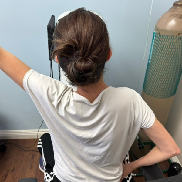 Nisreen raises one arm overhead during a pulmonary function test, using her Scolio-Pilates® corrections to open her ribcage and support her breath.