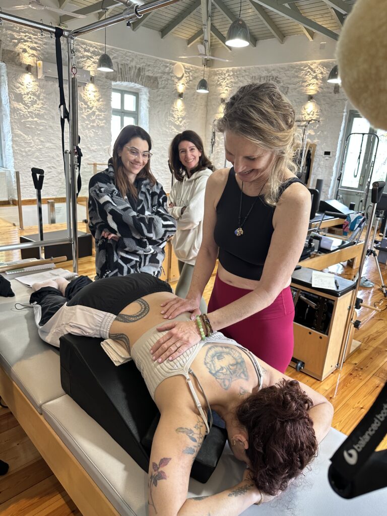 Hands-on scoliosis assessment during Scolio-Pilates® professional training, with students observing