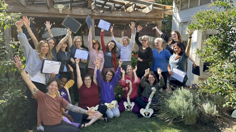 Scolio-Pilates® training graduates celebrating with certificates of continuing education and spine models