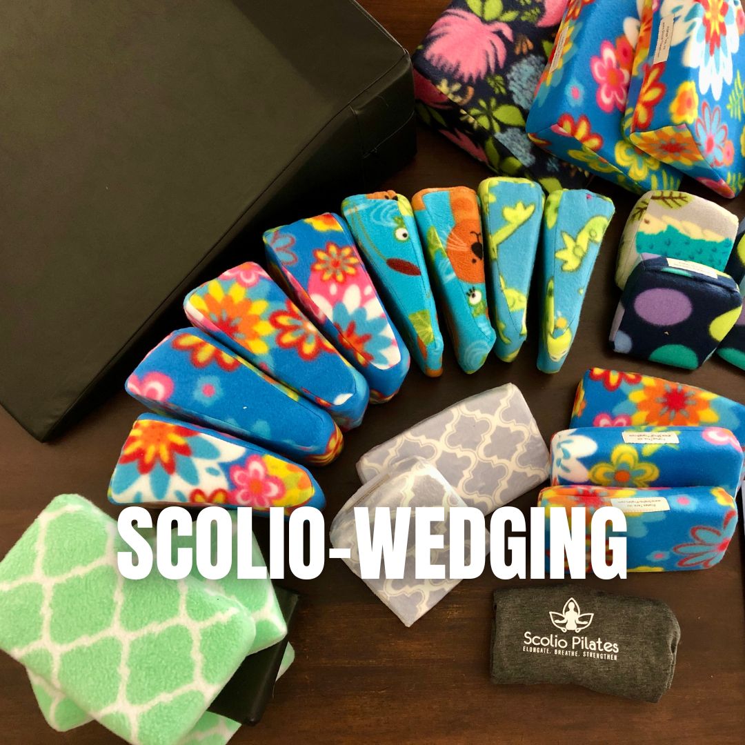 Assortment of colorful fabric-covered foam wedges used for Scolio-Wedging, a Scolio-Pilates prop for positioning the body during scoliosis exercises