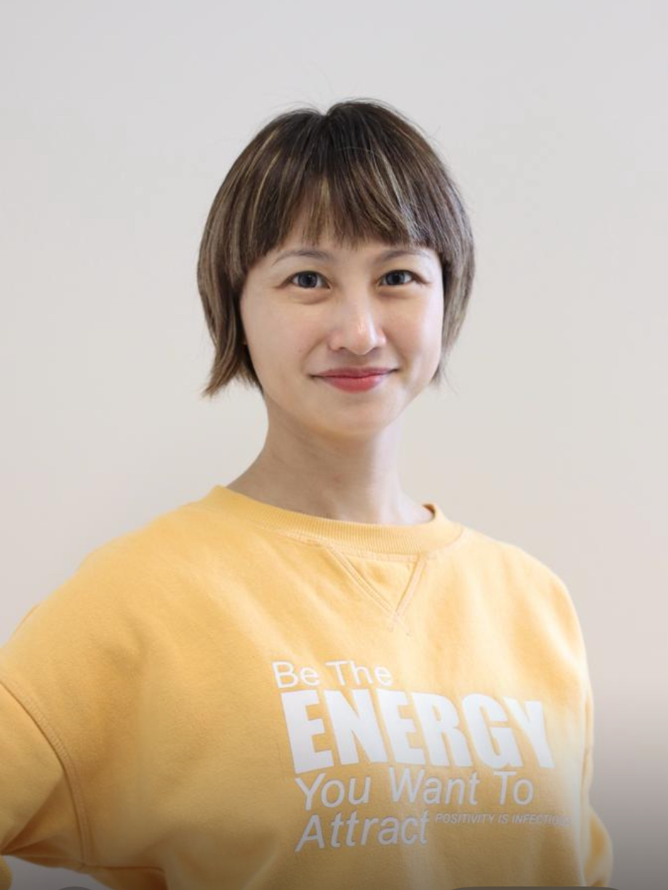 Joysha Hia Lisha, Authorized Scolio-Pilates practitioner in Singapore, smiling in a yellow sweatshirt
