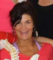 Nancy Reilly, Authorized Scolio-Pilates practitioner in Galveston, Texas, holding a spine model at her studio
